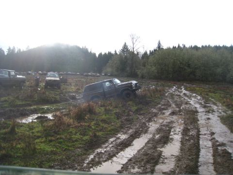 1978 Ford Bronco - Several off-road vehicles are stuck in the mud on a wet, overcast day.