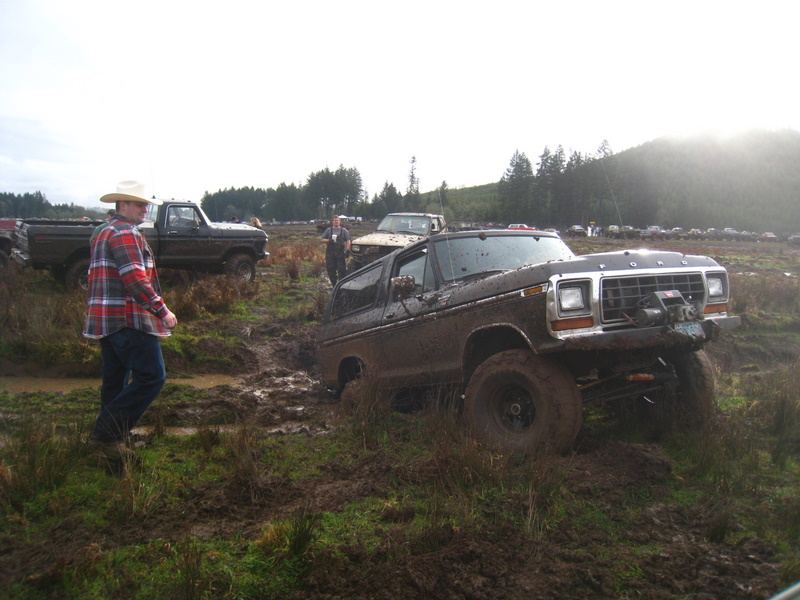 Muddy 1978 Ford Bronco with winch, other trucks in background