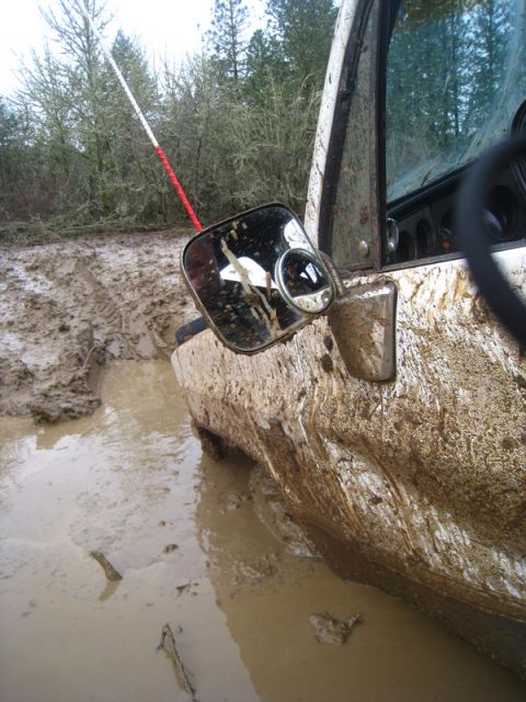1978 Ford Bronco - This off-road vehicle is deeply stuck in thick mud, with its side mirror and door heavily coated in dirt.