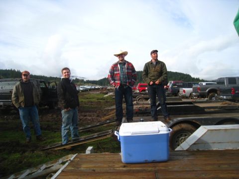 1978 Ford Bronco - A group of men stand on a trailer, with multiple trucks visible in the background of a muddy outdoor area.