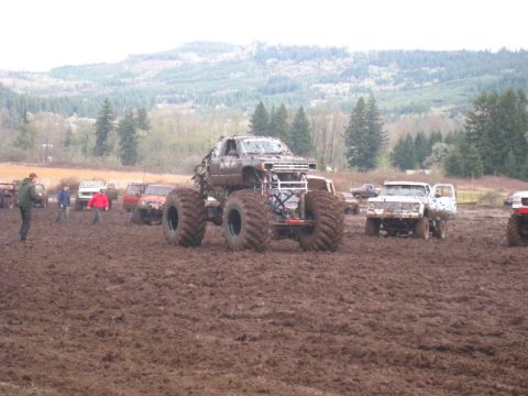 1978 Ford Bronco - Monster truck event with multiple vehicles and spectators in a muddy field.