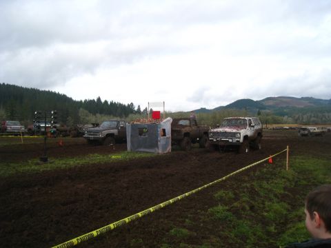 1978 Ford Bronco - Several trucks are in a muddy field, with a white SUV and a grey pickup truck prominently visible.