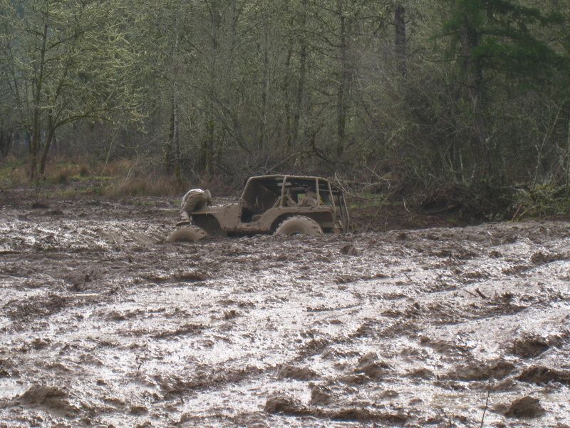 Off-road vehicle stuck deep in mud, side view. Watermark 'SUPERMOTORS.NET'