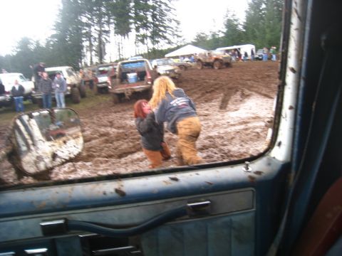 1978 Ford Bronco - Multiple off-road vehicles are stuck in the mud at an event, with people attempting to help.