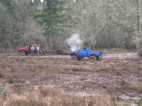 1978 Ford Bronco - Two trucks navigate a challenging muddy terrain with one appearing to have mechanical issues.