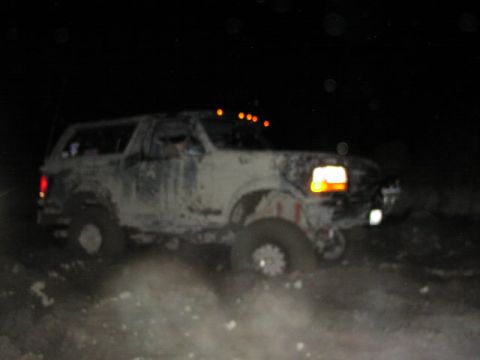 1981 Ford Bronco - Mud-covered Ford Bronco navigates rough terrain in the dark.