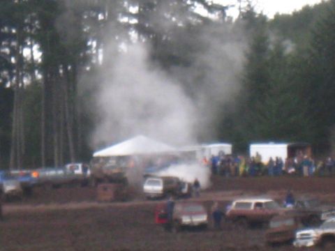 1978 Ford Bronco - Mud bog event with multiple vehicles and spectators under tents and trees.