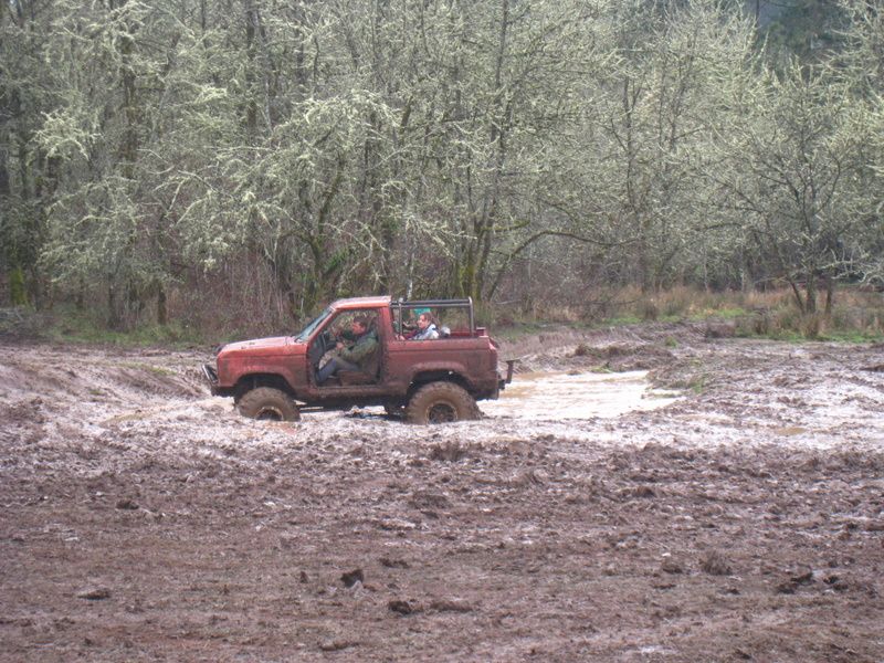 Red off-road vehicle stuck in mud with people inside