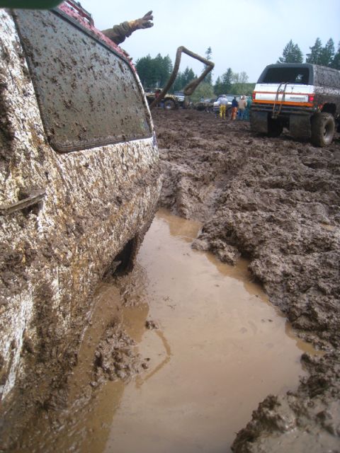 1978 Ford Bronco - Multiple off-road vehicles are stuck deep in the mud during an event.