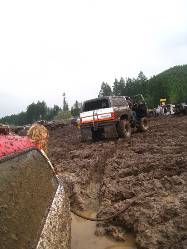 Muddy off-road vehicles stuck in a mire, with people around