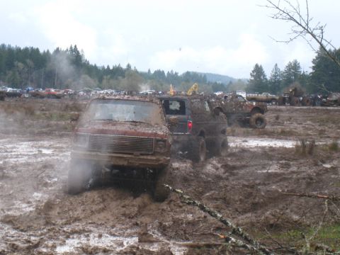 1978 Ford Bronco - Several vehicles are stuck in a muddy field under an overcast sky.