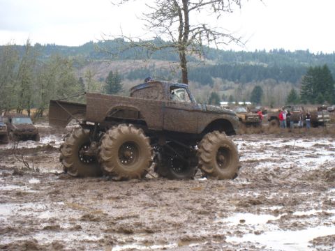 1978 Ford Bronco - Monster truck event with multiple vehicles navigating a muddy terrain.