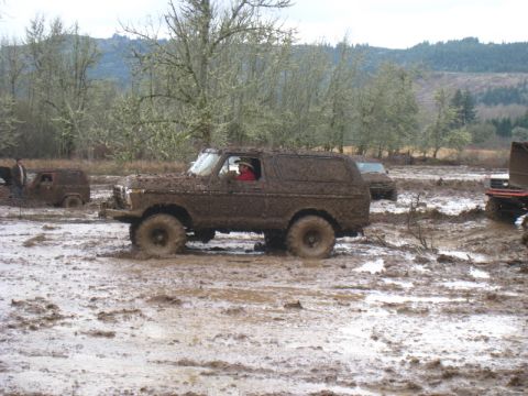 1978 Ford Bronco - A 1978 Ford Bronco navigates a muddy terrain, with other vehicles visible in the background.