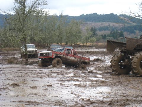 1978 Ford Bronco - Multiple off-road vehicles are stuck in deep mud during an event.