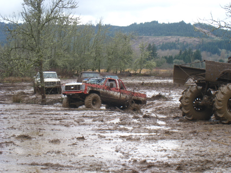 Red pickup truck stuck in mud, 3q-front view