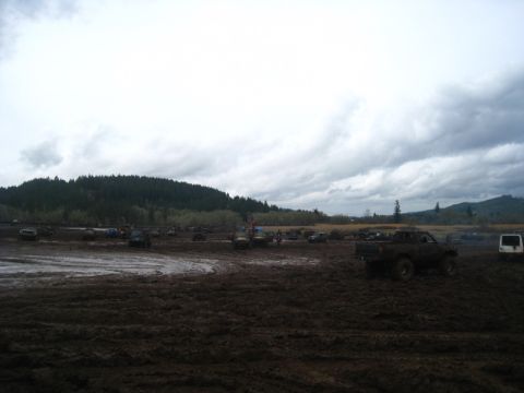 1978 Ford Bronco - Multiple vehicles are seen in a muddy field under a cloudy sky.