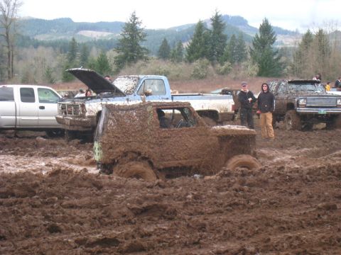 1978 Ford Bronco - Several trucks are stuck in deep mud during an off-road event.