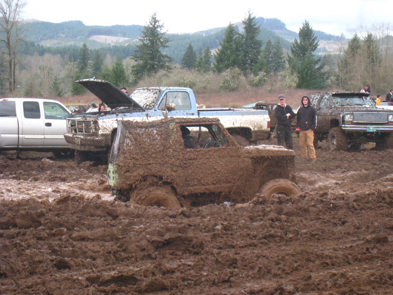 Mud-covered SUV stuck in a muddy field with other trucks