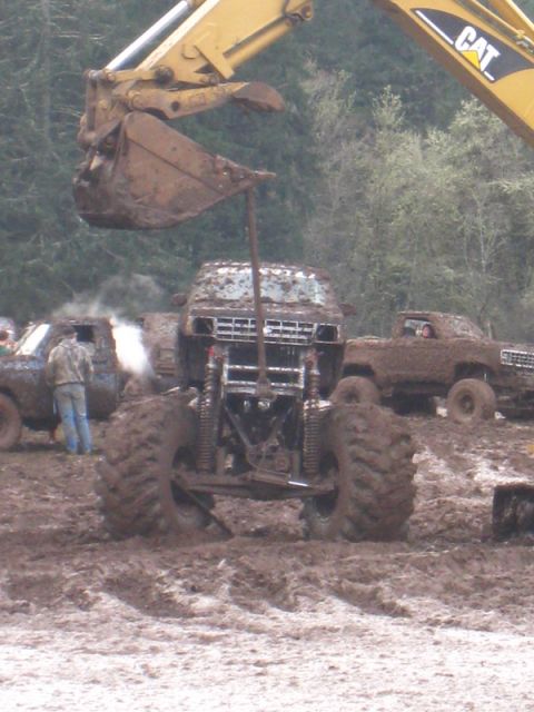 1978 Ford Bronco - Multiple modified trucks stuck in deep mud during an off-road event.