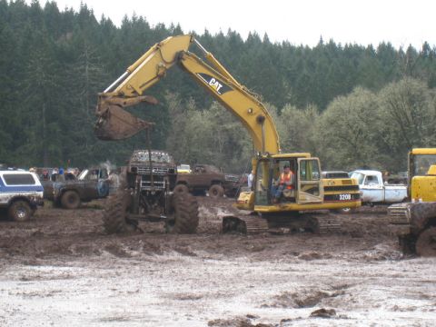 1978 Ford Bronco - An excavator is actively working in a muddy area, with various trucks present in the background.