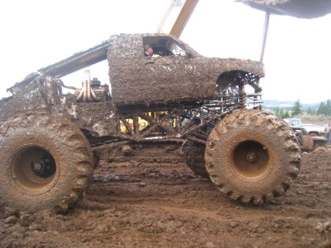 1978 Ford Bronco - A heavily mud-caked monster truck navigates a muddy track, with another vehicle visible in the background.