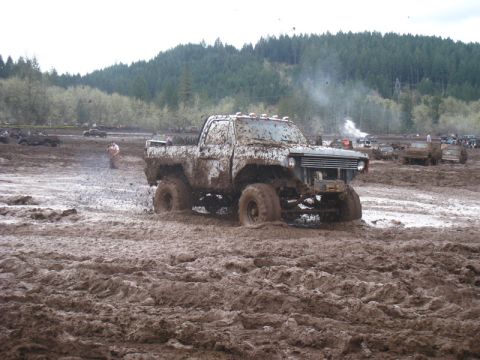 1978 Ford Bronco - Pickup truck struggling in a mud bog with other vehicles visible in the distance.