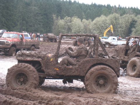 1978 Ford Bronco - Off-road vehicles navigate a muddy course, covered in mud.