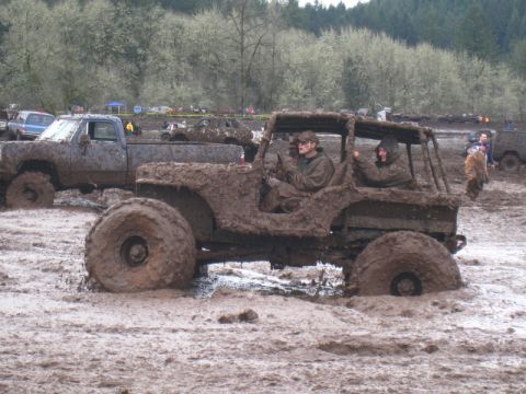 1978 Ford Bronco - Off-road vehicles navigate a muddy terrain during an event.
