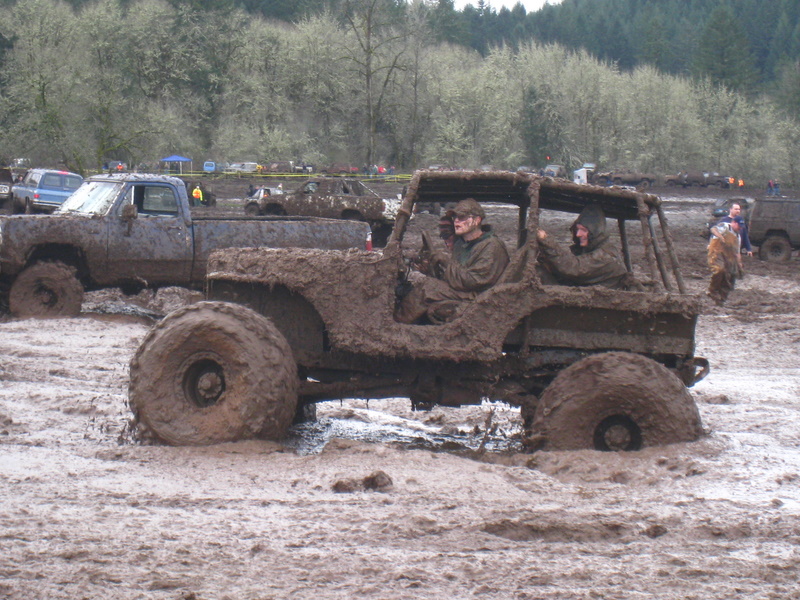 Mud-covered off-road vehicles stuck in mud, with people inside