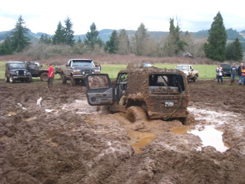 1978 Ford Bronco - Several vehicles are stuck in deep mud during an off-road event.