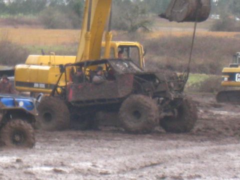 1978 Ford Bronco - An off-road vehicle navigates a muddy terrain, with heavy machinery in the background.
