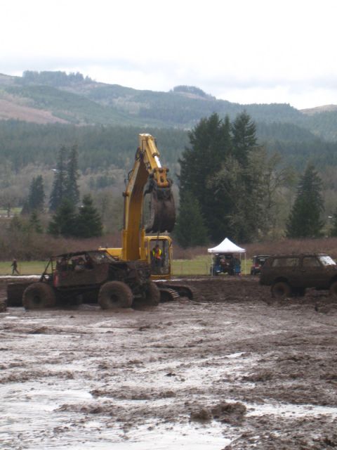 1978 Ford Bronco - An excavator operates in a muddy field while off-road vehicles participate in a mud bogging event.