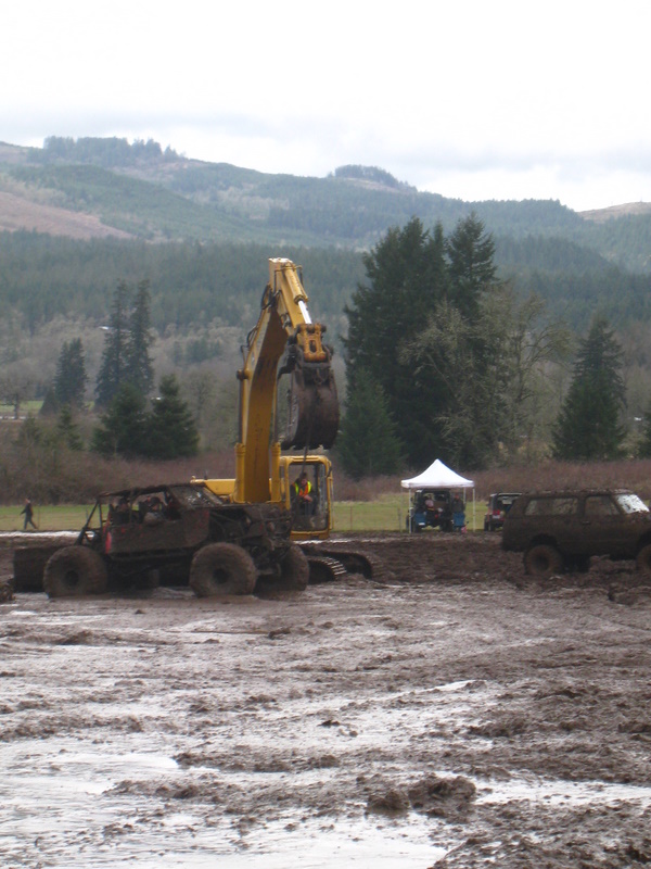 Mud bogging scene with excavator, off-road buggy, and SUV in muddy terrain