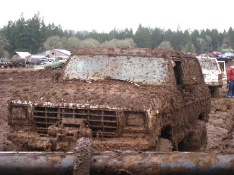 1978 Ford Bronco - This 1978 Ford Bronco is completely covered in mud, stuck in a muddy field with other vehicles nearby.