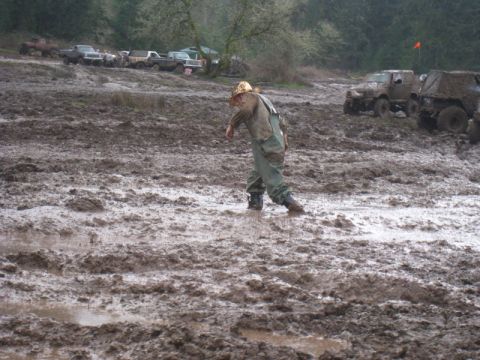 1978 Ford Bronco - Off-road vehicles parked in a muddy area with a person walking through the mire.