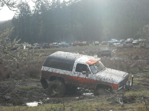1978 Ford Bronco - This SUV is stuck in the mud, with many other vehicles visible in the background during an off-road event.