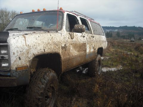 1978 Ford Bronco - A heavily mud-splattered SUV navigates a muddy terrain with another vehicle visible in the distance.