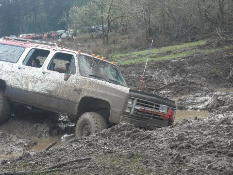 1978 Ford Bronco - Muddy Chevrolet K5 Blazer struggling in a muddy off-road course with other vehicles nearby.