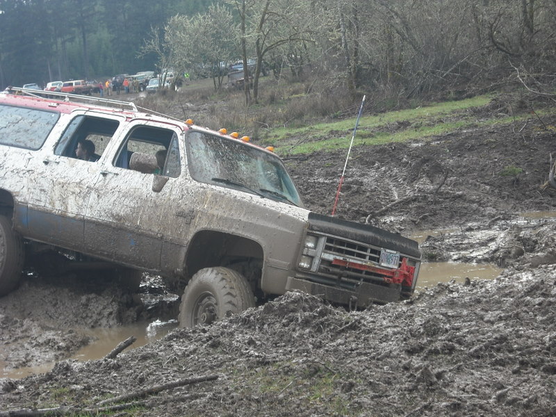 Muddy 1980s Chevrolet K5 Blazer stuck in deep mud, other vehicles in background