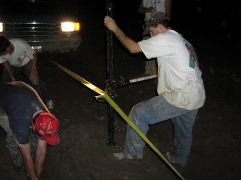 1981 Ford Bronco - A group of people use a high-lift jack near a 1981 Ford Bronco in a muddy off-road setting.