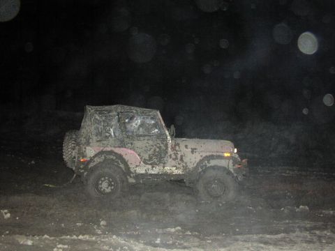 1981 Ford Bronco - Jeep CJ-7 covered in mud, navigating a dark, muddy terrain.