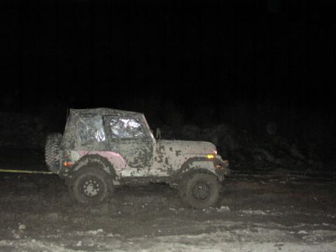 1981 Ford Bronco - A Jeep is covered in mud after driving through a dark, muddy area.
