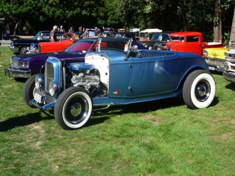 1969 Lincoln Continental - A blue 1932 Ford hot rod roadster is displayed at an outdoor car show with other vehicles.