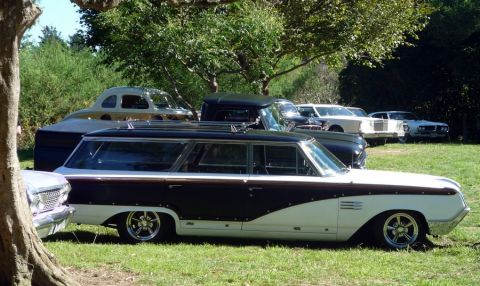 1969 Lincoln Continental - Custom two-tone station wagon with chrome wheels is parked on grass with other vehicles.
