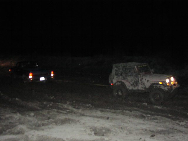 Two off-road vehicles being towed at night, one in front, one behind