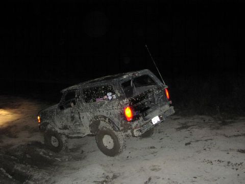 1981 Ford Bronco - This SUV is covered in mud and driving on a dirt road in the dark.