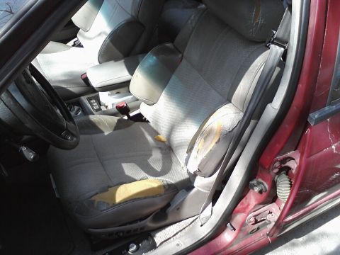 1995 Ford Taurus - Interior of a car showing significant wear on the seats and door panel.