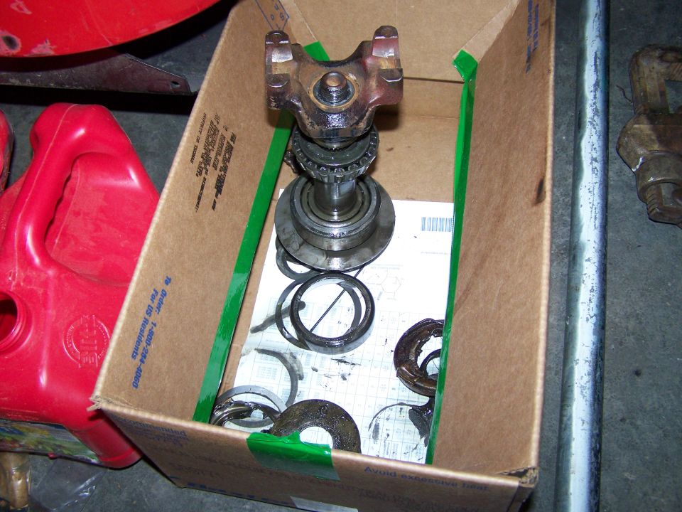 Cardboard box with driveshaft U-joint, bearings, and seals. Red plastic gas can nearby