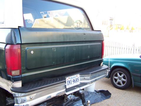1992 Ford Bronco - Rear view of a 1992 Ford Bronco showing the bumper and tailgate, with another vehicle visible to the side.