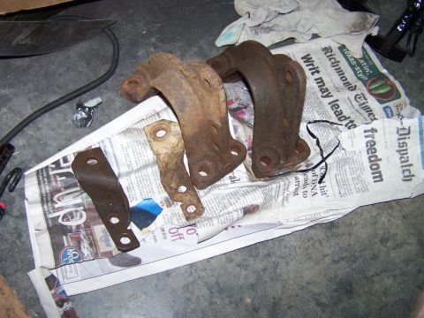 1992 Ford Bronco - Several rusted metal brackets are laid out on a newspaper, suggesting they are parts for a vehicle restoration project.